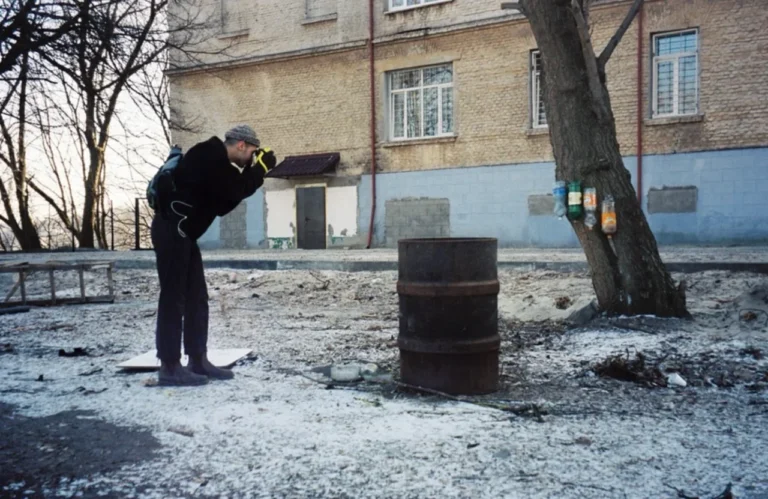 Константин Гузенко фотографирует на камеру в заснеженном дворе возле бочки