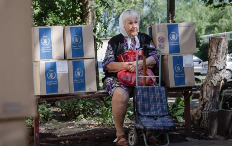 Пожилая женщина с коробками WFP на фоне сокращения финансирования ООН