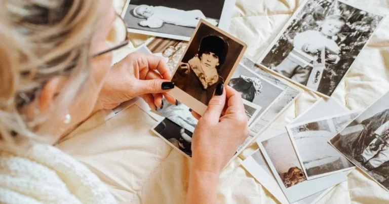 Жінка розглядає старі фотографії дитини, відчуваючи ностальгію за минулим