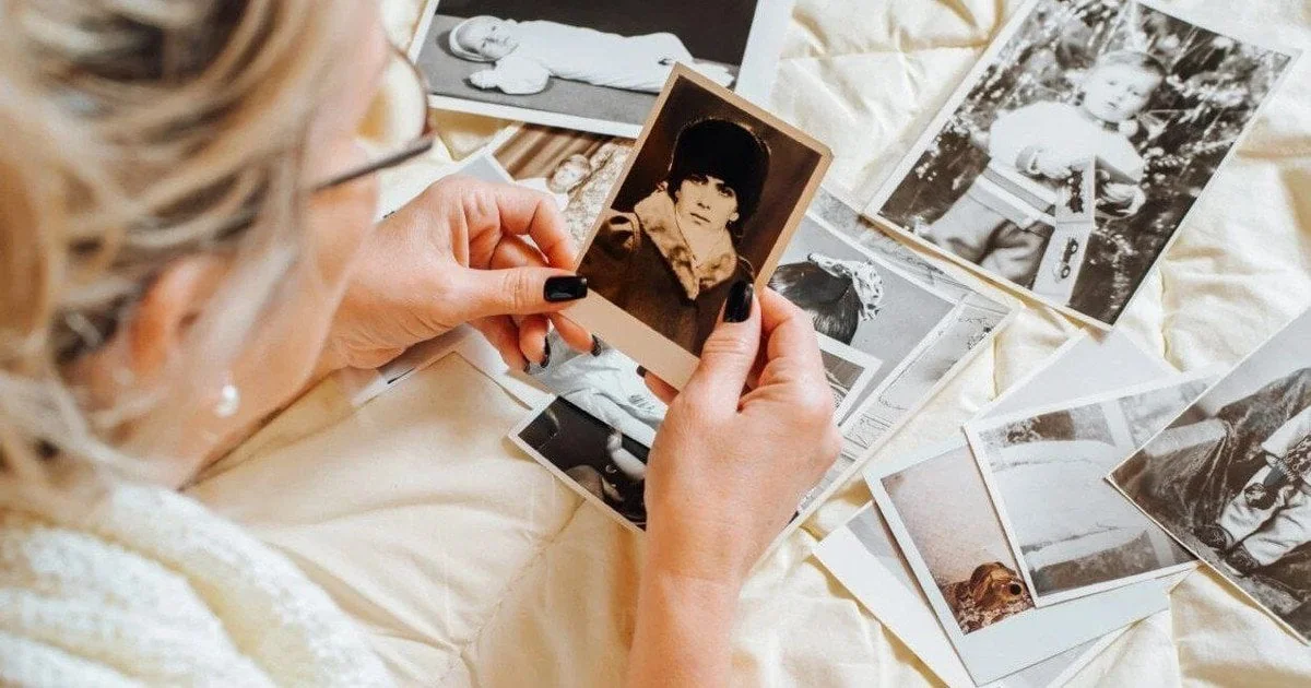 Жінка розглядає старі фотографії дитини, відчуваючи ностальгію за минулим