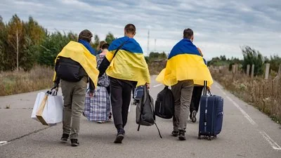 Три юнаки з прапорами України йдуть з окупації на підконтрольну територію з речами