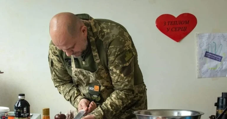 Військовий тилу в формі ЗСУ готує їжу на кухні, щоб прогодувати родину