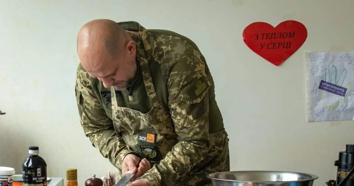 Військовий тилу в формі ЗСУ готує їжу на кухні, щоб прогодувати родину
